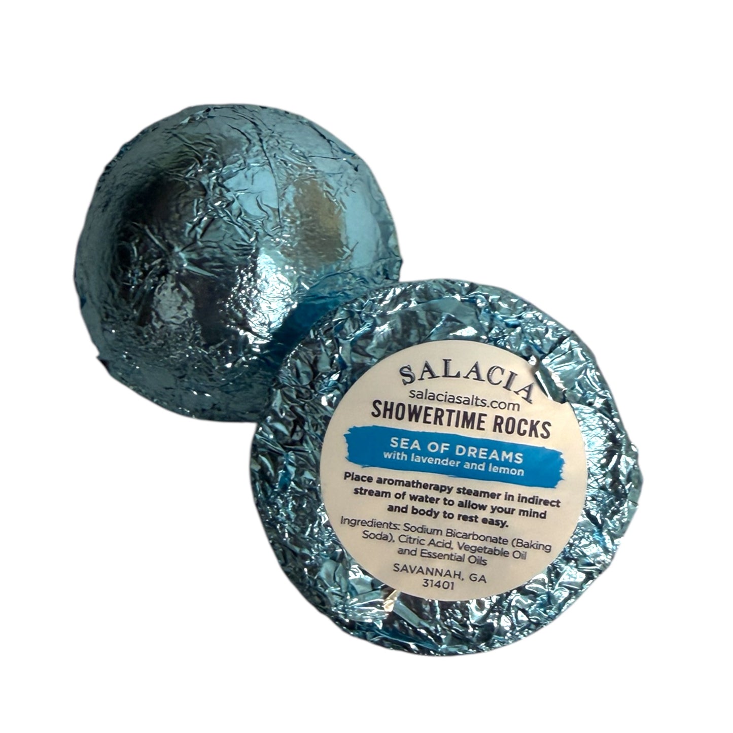 Two round bath bombs wrapped in crinkled silver foil, with one showing a white paper label that reads 'SALACIA showertime rocks Sea of Dreams with lavender and lemon'.